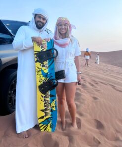 safari guide with a tourist carrying a sand board over desert safari tour