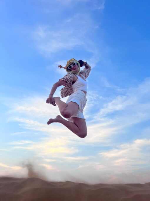 desert photoshoot tourist jumping off the sand dune
